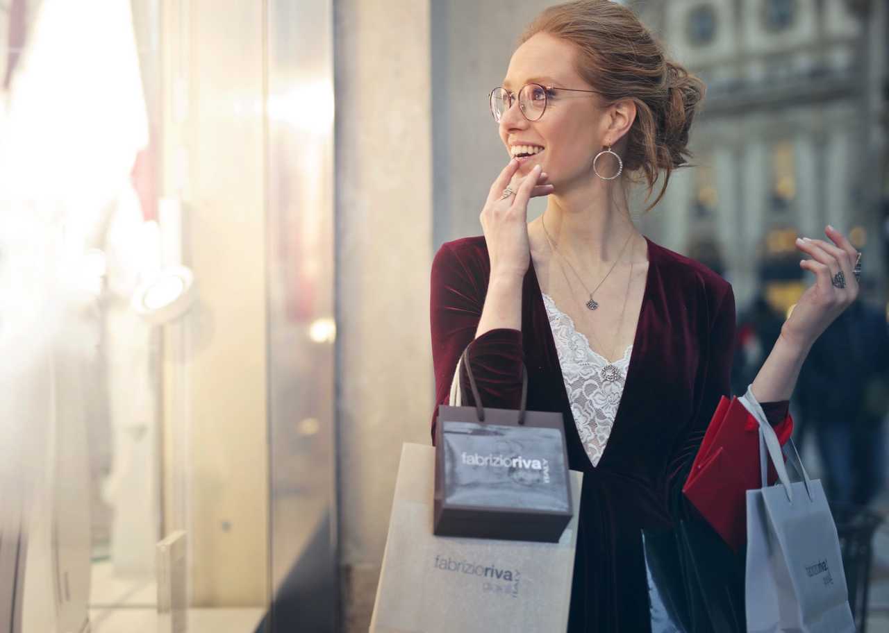 woman with shopping bags attracted by shiny shop window
