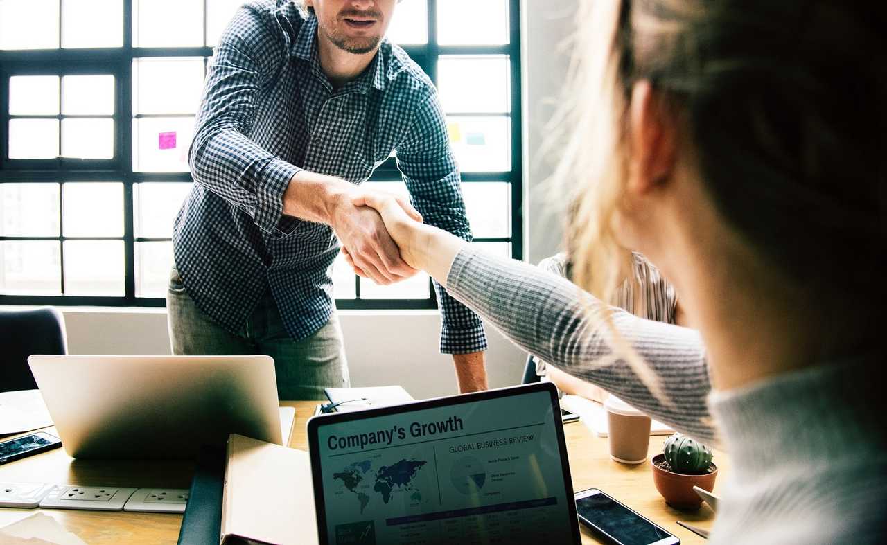 people making a deal over a table with laptops