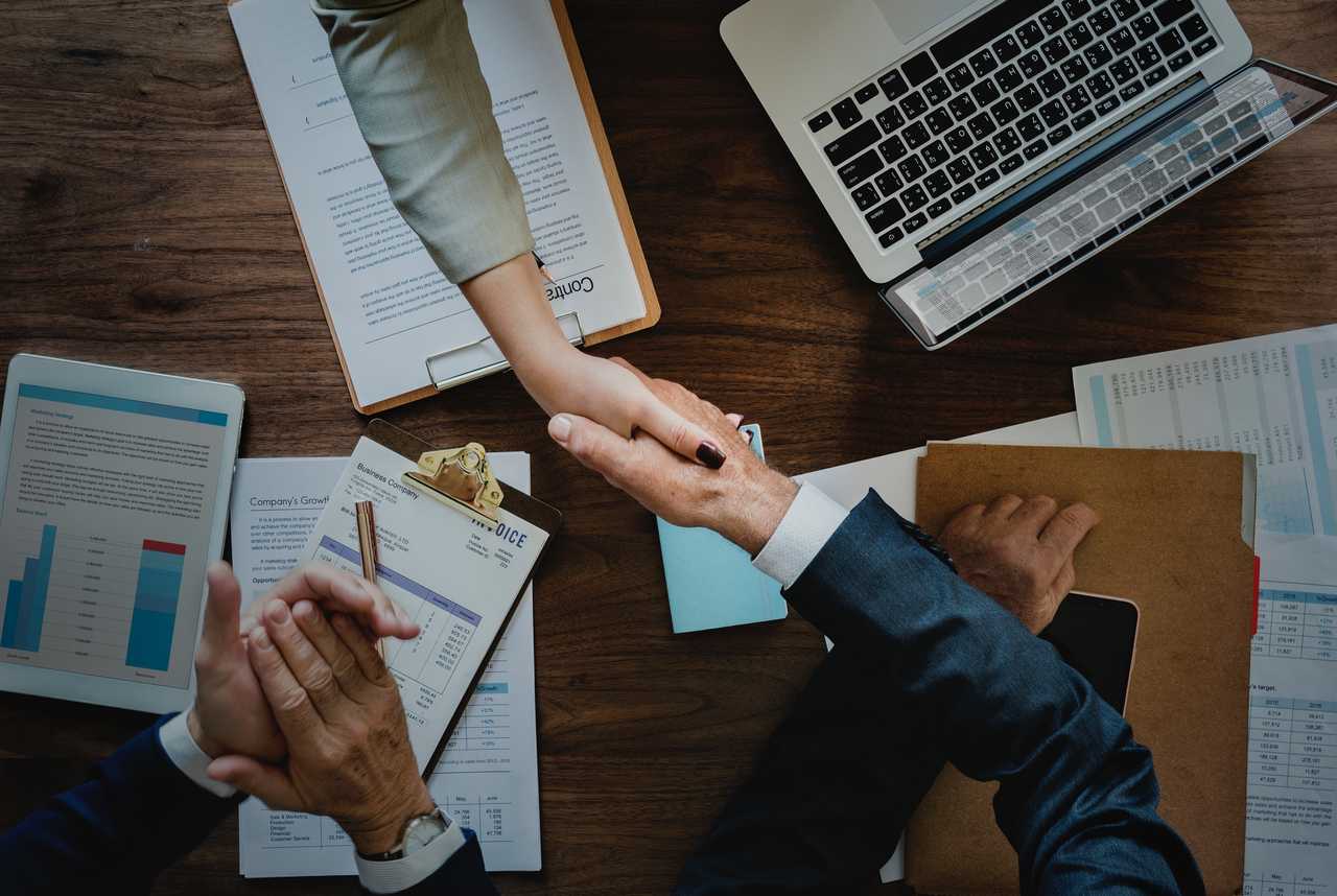 people shaking hands over table in a business meeting